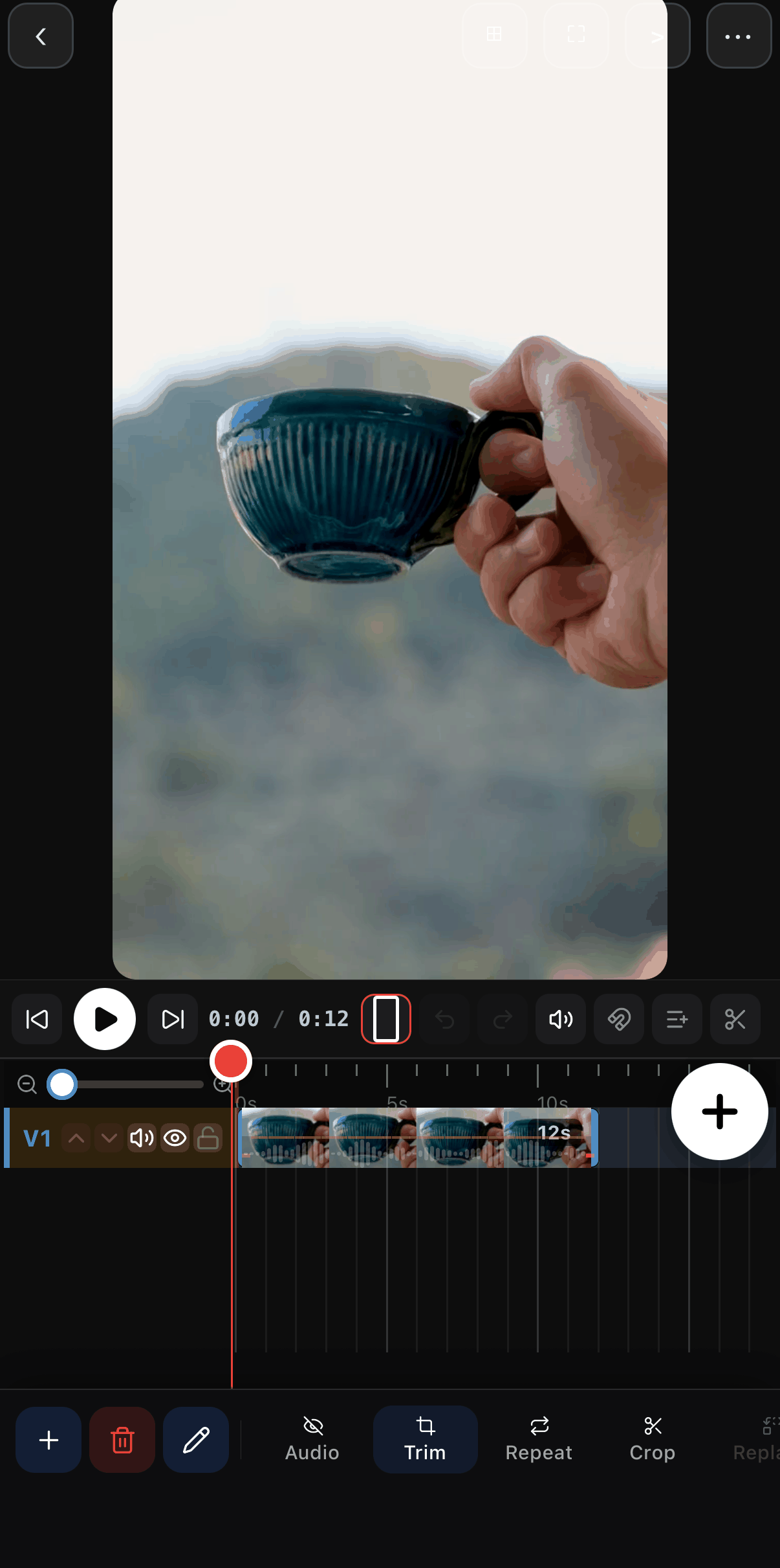 The ExpoCut editor with a square canvas showing a hand holding a blue ceramic mug; the clip on the V1 row is selected and trimmed to 12 s, and the clip toolbar shows Audio, Trim, Repeat and Crop.